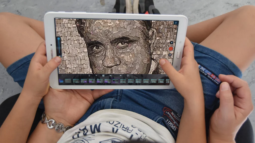 Fotografia di bambino con mamma che guardano un tablet che presenta una immagine di Beniamino Gigli.