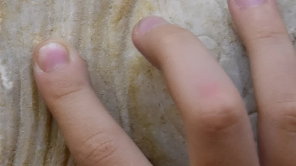 Immagine che raffigura la mano di un bambino che tocca una statua di marmo