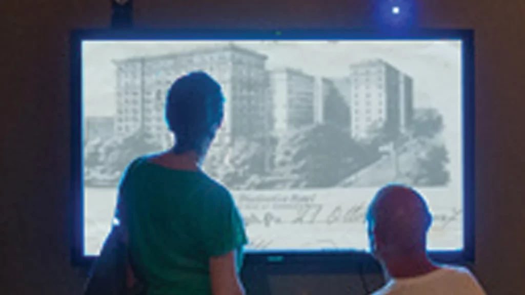 Immagine di visitatori di un museo che guardano un video su grande schermo